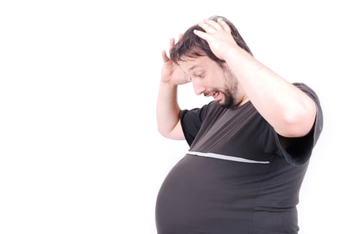 Pregnant man with big stomach with surprised expression on face