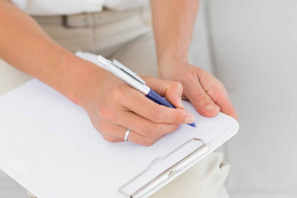 Therapist taking notes on clipboard at therapy session Therapist taking notes on clipboard at therapy session